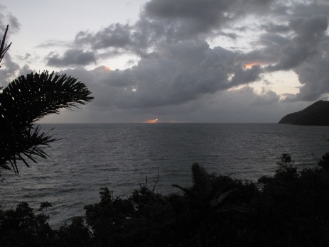 Suns rays squeeze through the early morning cloud cover at Etty Bay on Eclipse Day
